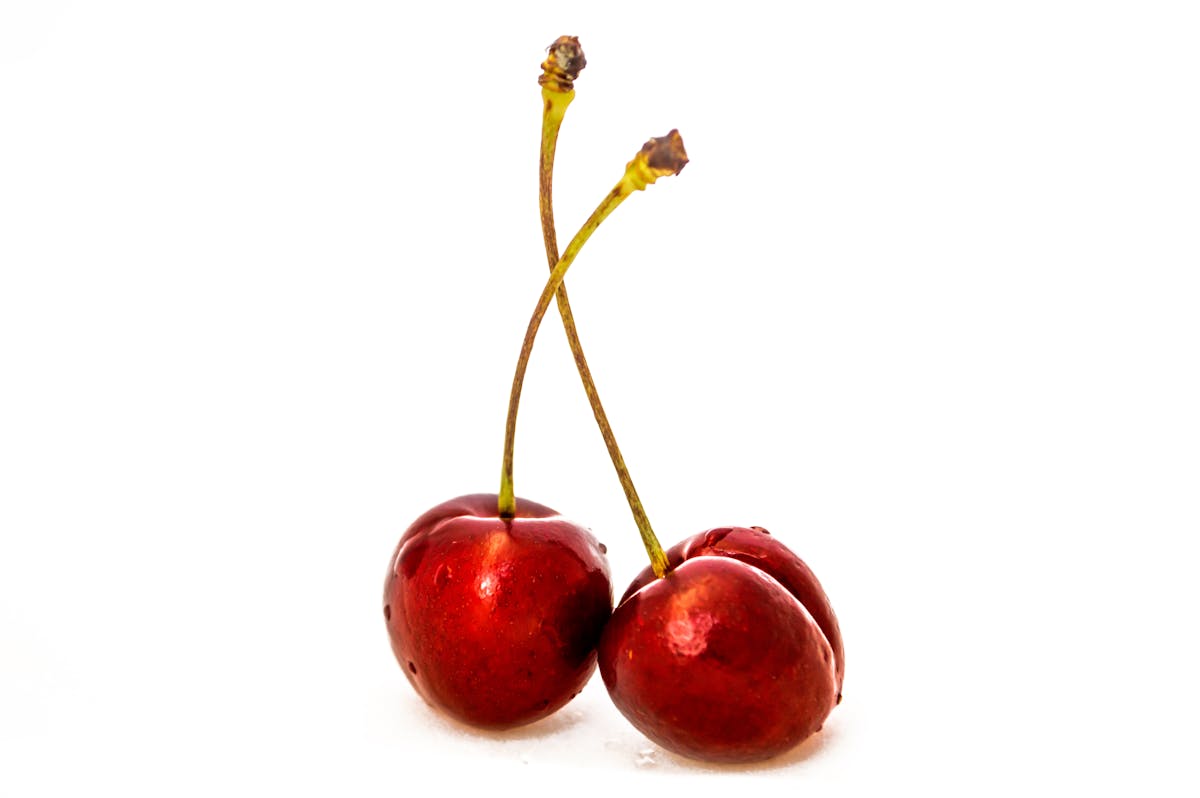 Two ripe red sweet cherries — premium fruit size commands significantly higher market prices