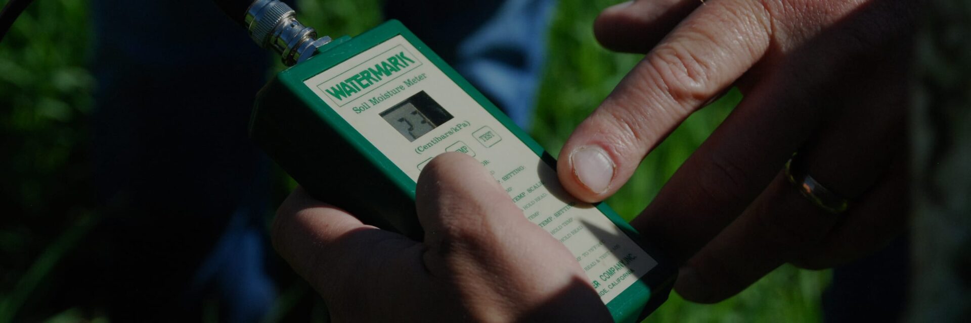 Handheld soil moisture meter being read in the field